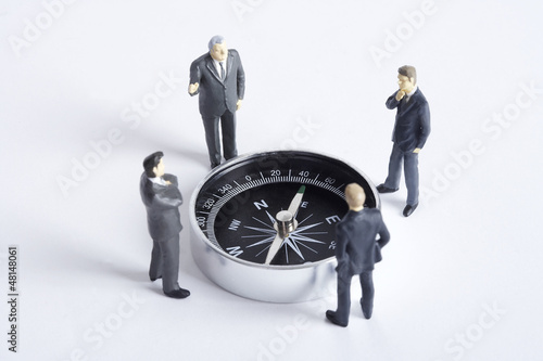 Photo: Businessman figurines standing and looking at compass Businessman figurines standing and looking at compass