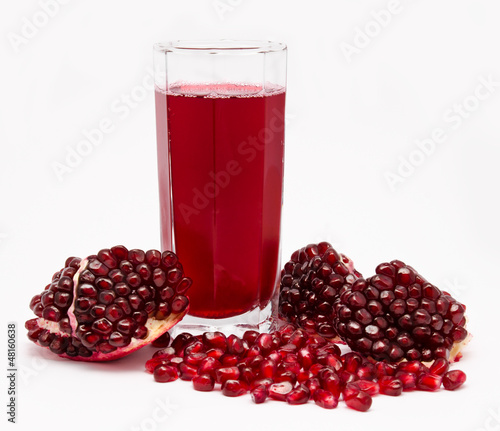 Photo: Pomegranate juice in glass and pomegranates isolated on white Pomegranate juice in glass and pomegranates isolated on white