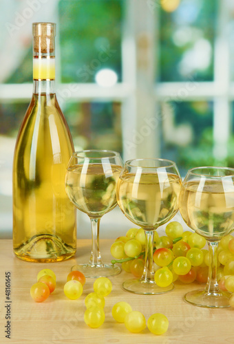 Photo: White wine in glass with bottle on window background White wine in glass with bottle on window background