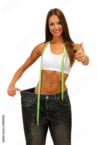 Photo: beautiful young woman with big jeans and measuring tape, beautiful young woman with big jeans and measuring tape,