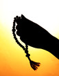 female hands with rosary, on beige background