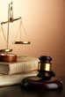 Golden scales of justice, gavel and books on brown background