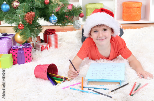 Photo: Little boy in Santa hat writes letter to Santa Claus Little boy in Santa hat writes letter to Santa Claus