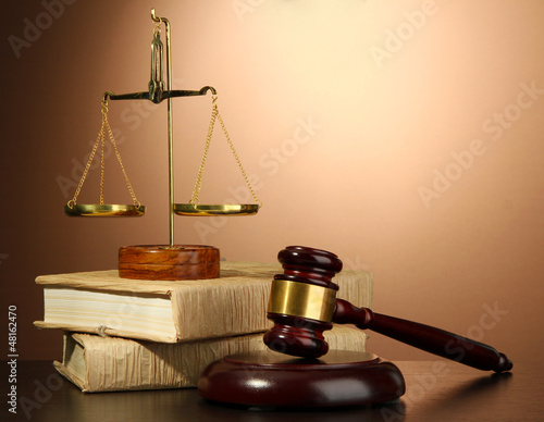 Photo: Golden scales of justice, gavel and books on brown background Golden scales of justice, gavel and books on brown background
