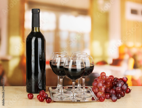 Photo: Red wine in glass and bottle on room background Red wine in glass and bottle on room background