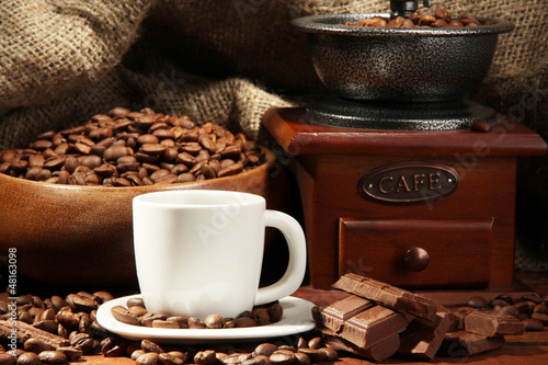 Photo: Coffee grinder and cup of coffee on burlap background Coffee grinder and cup of coffee on burlap background