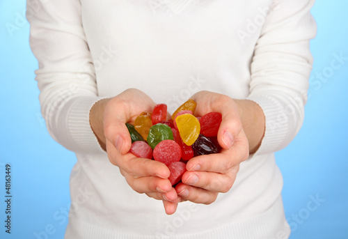 Photo: Hands full of sweets on blue background Hands full of sweets on blue background
