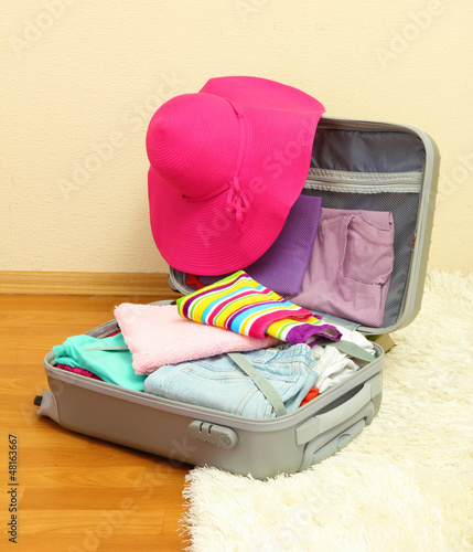 Photo: Open silver suitcase with clothing in room Open silver suitcase with clothing in room