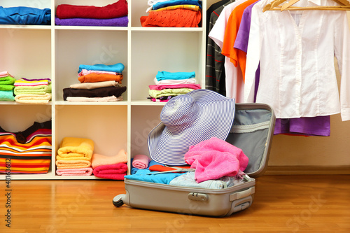 Photo: Open silver suitcase with clothing in room Open silver suitcase with clothing in room