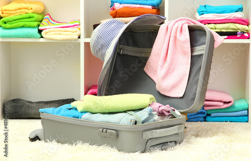 Photo: Open silver suitcase with clothing in room Open silver suitcase with clothing in room