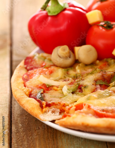 Photo: Fresh italian pizza in plate on a wooden surface Fresh italian pizza in plate on a wooden surface