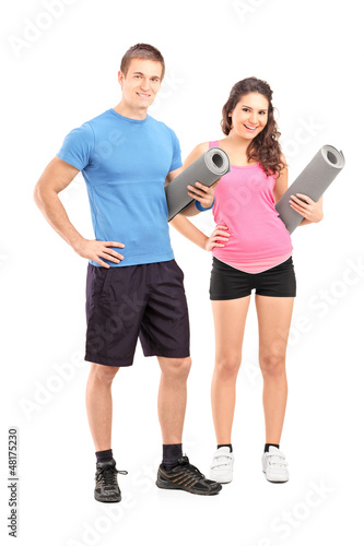 Photo: Two young athletes holding exercising mats Two young athletes holding exercising mats