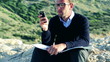 Young man sitting on rocks near the vantage point with cellphone