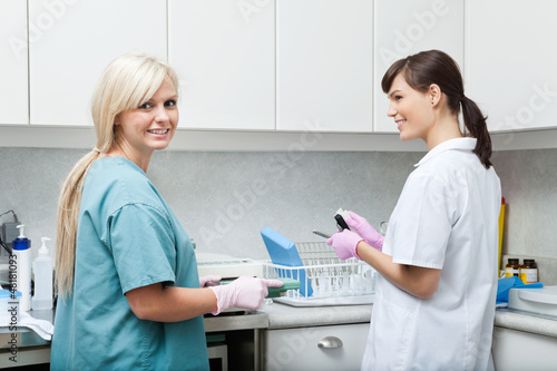 Photo: Smiling Dentist With Assistant Cleaning Medical Instruments At C Smiling Dentist With Assistant Cleaning Medical Instruments At C