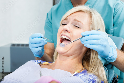 Photo: Dentist Treating A Female Patient At Clinic Dentist Treating A Female Patient At Clinic