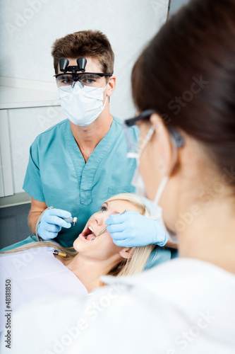 Photo: Dentist And Female Assistant Treating A Patient At Clinic Dentist And Female Assistant Treating A Patient At Clinic