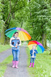 mother and her daughter with umbrellas in spring alley