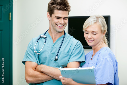 Photo: Young Female Nurse Showing Clipboard To Male Vet Young Female Nurse Showing Clipboard To Male Vet