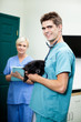 Veterinarian Doctor Carrying A Dog With Female Nurse Holding Cli
