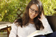 Hübsche Frau mit Brille liest ein Buch auf der Terrasse