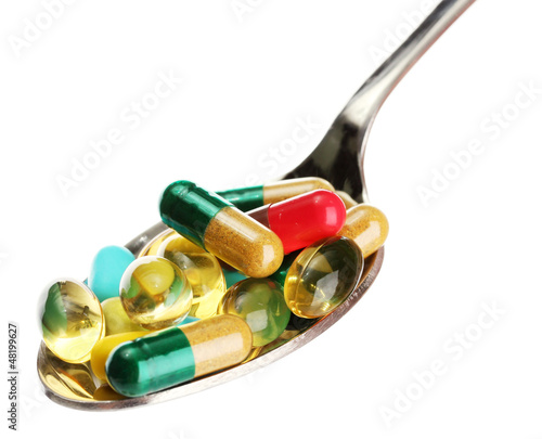 Photo: spoon with colorful capsules and pills, isolated on white spoon with colorful capsules and pills, isolated on white