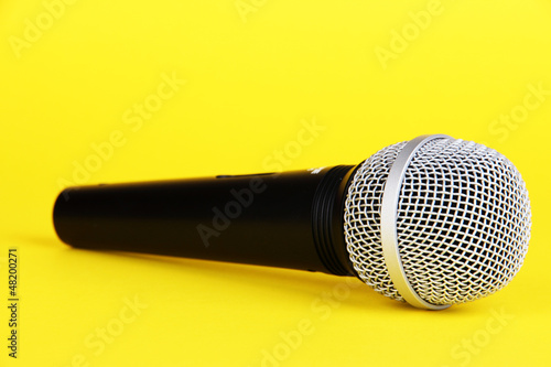 Photo: Black microphone on yellow background Black microphone on yellow background