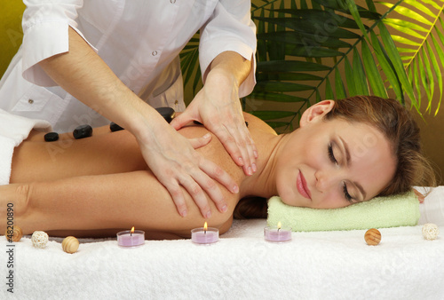 Photo: beautiful young woman in spa salon getting massage with spa beautiful young woman in spa salon getting massage with spa