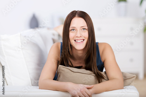 Photo: lächelnde junge frau liegt auf dem sofa lächelnde junge frau liegt auf dem sofa