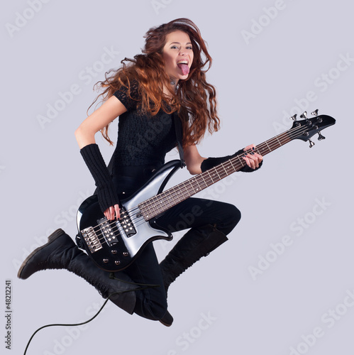 Photo: Beautiful smiling girl with bass guitar jumping high in the air Beautiful smiling girl with bass guitar jumping high in the air