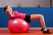 Beautiful young girl exercising abdomen muscles in the gym