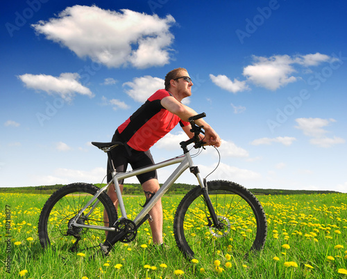 Photo: biker with the mountain bike in the dandelion field biker with the mountain bike in the dandelion field
