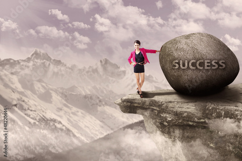 Photo: Businesswoman and rock of success outdoor Businesswoman and rock of success outdoor