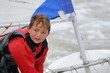 enfant en combinaison de voile avec un optimist