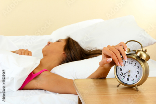 Photo: young beautiful woman in bed and alarm clock young beautiful woman in bed and alarm clock