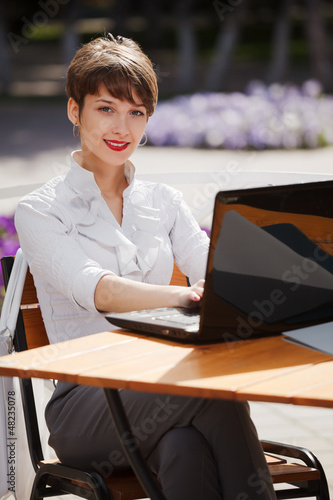 Photo: Young businesswoman with laptop at a sidewalk cafe Young businesswoman with laptop at a sidewalk cafe
