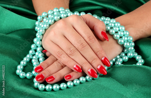 Photo: Female hands holding beads on color background Female hands holding beads on color background