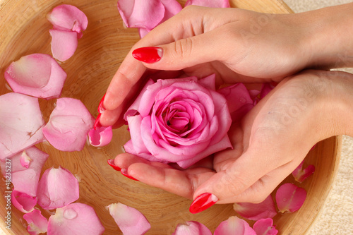 Photo: woman hands with wooden bowl of water with petals woman hands with wooden bowl of water with petals