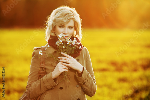 Photo: Young woman with a flowers in autumn field Young woman with a flowers in autumn field