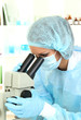 Young scientist looking into  microscope in  laboratory.