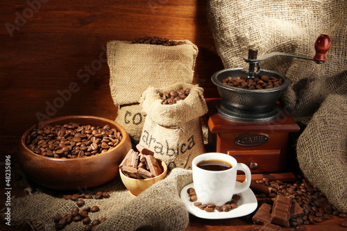 Photo: Coffee grinder and cup of coffee on brown wooden background Coffee grinder and cup of coffee on brown wooden background