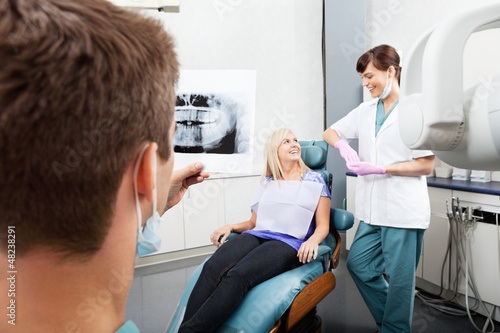 Photo: Dentist Examining X-Ray Image With Female Assistant Communicatin Dentist Examining X-Ray Image With Female Assistant Communicatin
