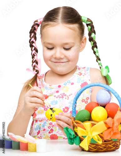 Photo: Little girl is painting eggs preparing for Easter Little girl is painting eggs preparing for Easter