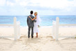 Just married couple standing by a fence towards this ocean