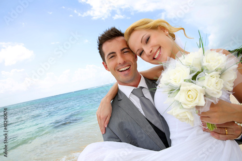 Photo: Groom holding bride in his arms at the beach Groom holding bride in his arms at the beach