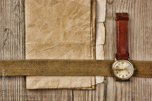 Photo: vintage paper and old broken watch on wooden boards vintage paper and old broken watch on wooden boards