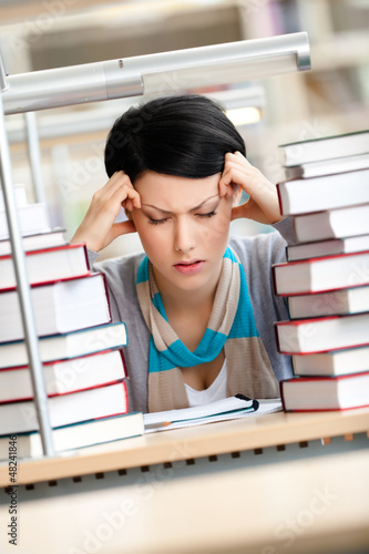 Photo: Tired young woman with headache sitting at the desk Tired young woman with headache sitting at the desk