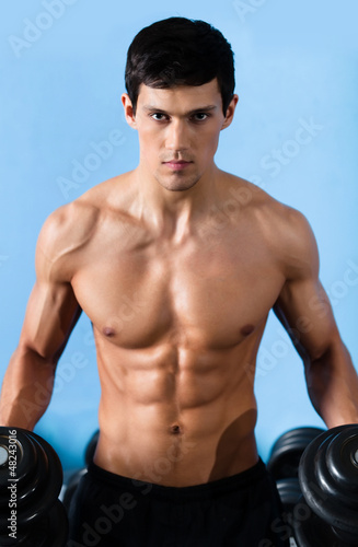 Photo: Handsome muscular man with sexy body uses his dumbbell Handsome muscular man with sexy body uses his dumbbell