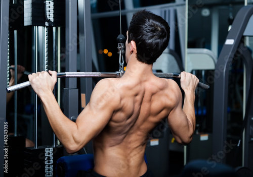 Photo: Athletic young man works out on training apparatus Athletic young man works out on training apparatus
