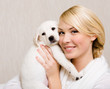 Photo: Woman keeping white labrador puppy near her face Woman keeping white labrador puppy near her face