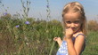 Little Girl Playing and Smelling Flowers on the Field